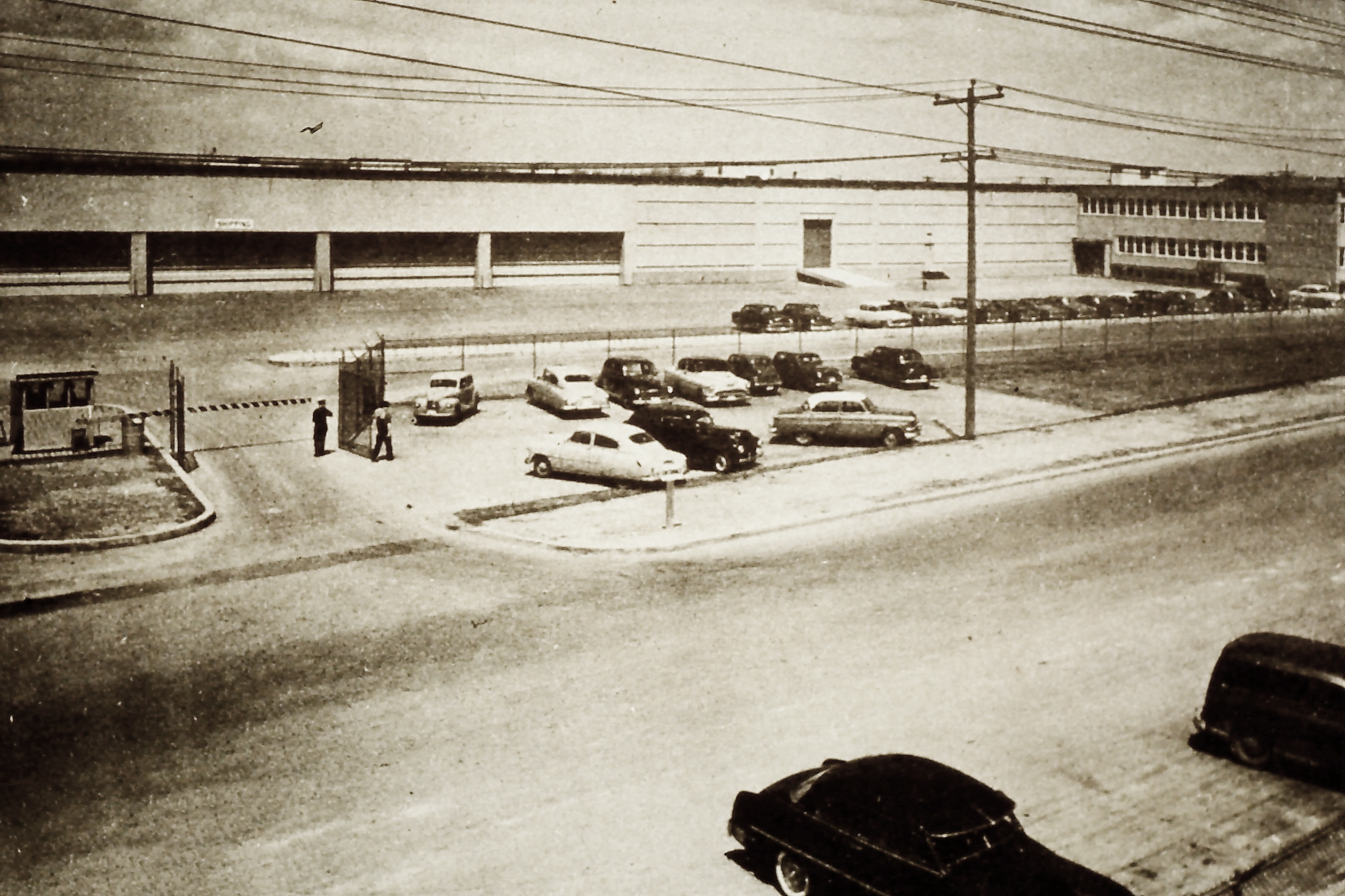 A black and white photo of cars parked outside of a building along Carl Hall Road.