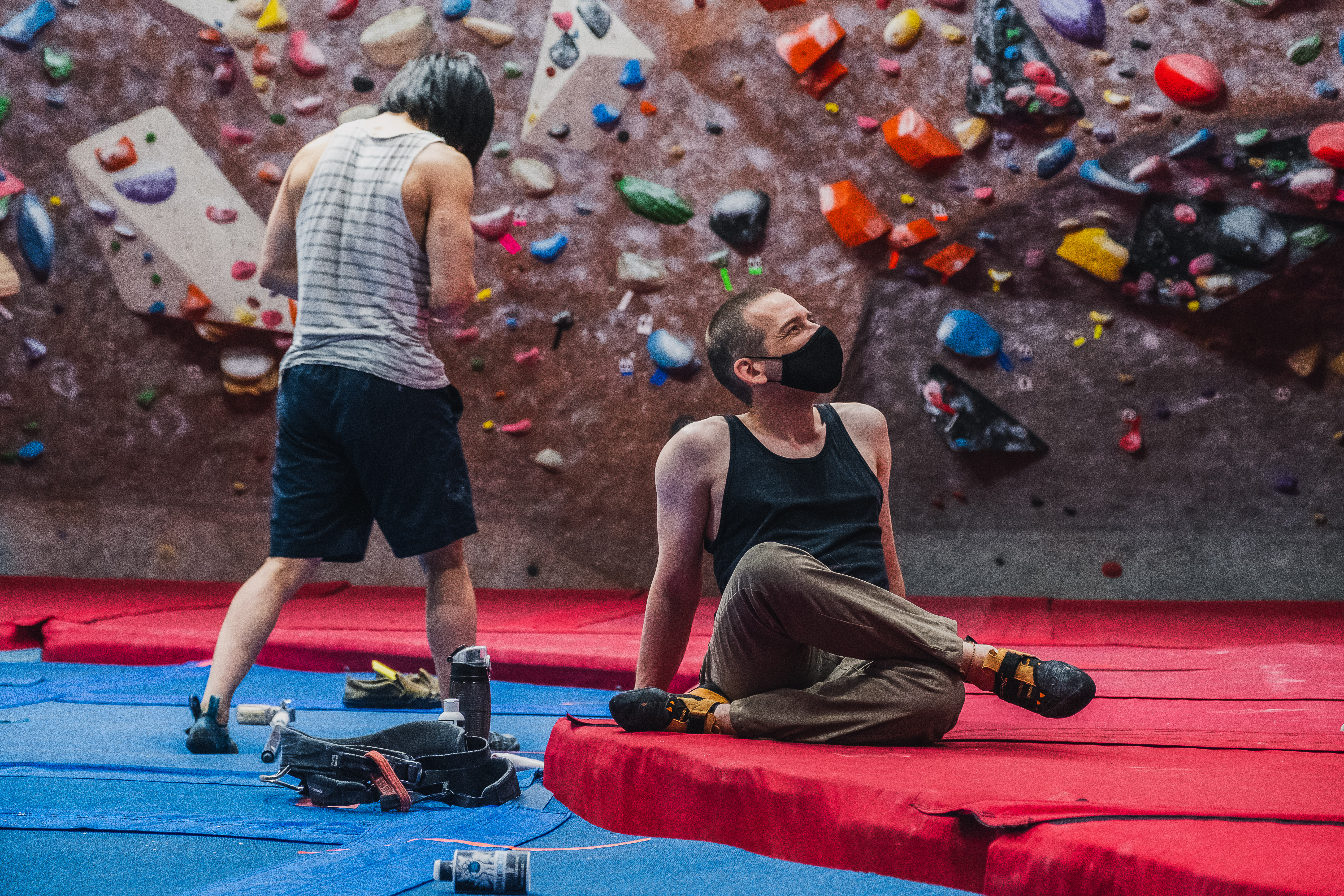 Two climbers in front of a wall covered in colourful holds.