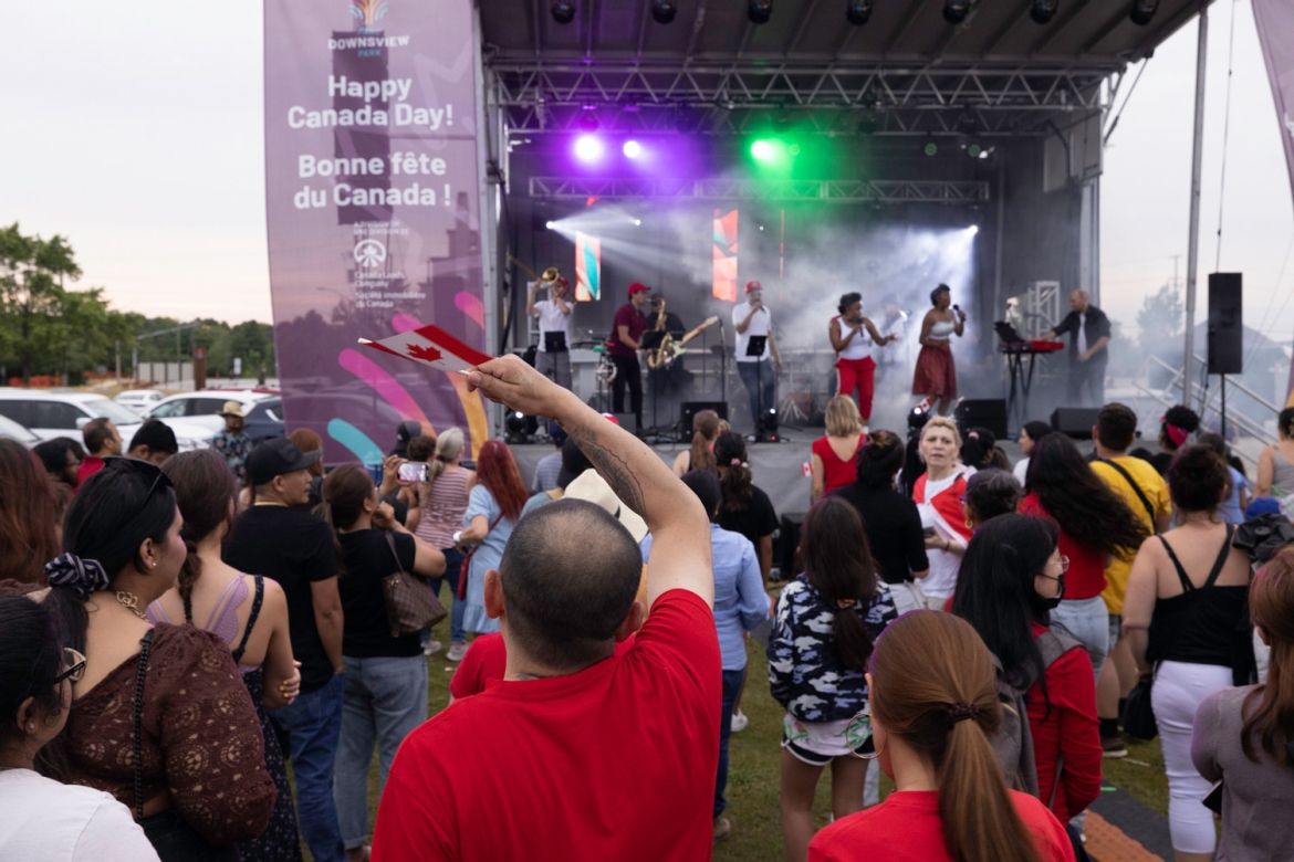 A crowd of people dancing and waving Canadian flags in front of the stage