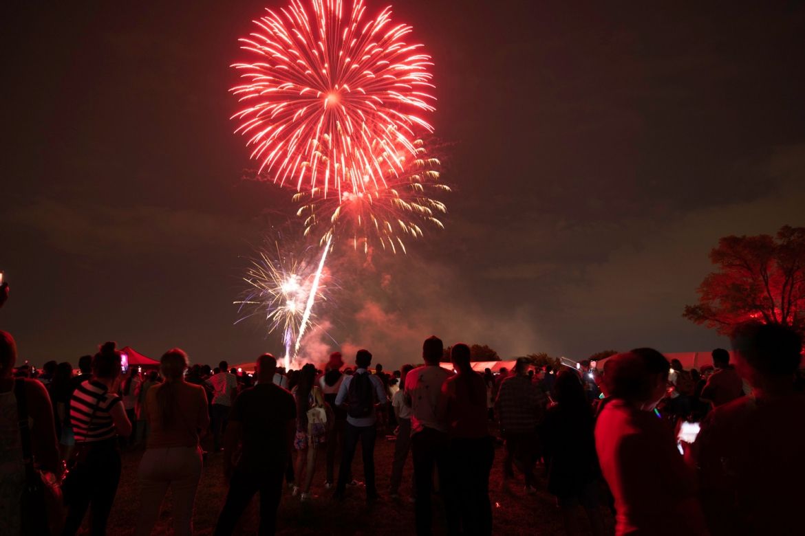 A crowd of people watching a fireworks show at the Festival Terrace.