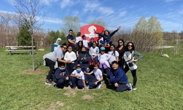 A group of students posing in front of a giant Muskoka chair at Downsview Park.