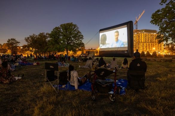 An inflatable screen showing a movie to a crowd at night