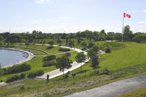 The lake, a paved path, grass, trees, and a Canadian flag.