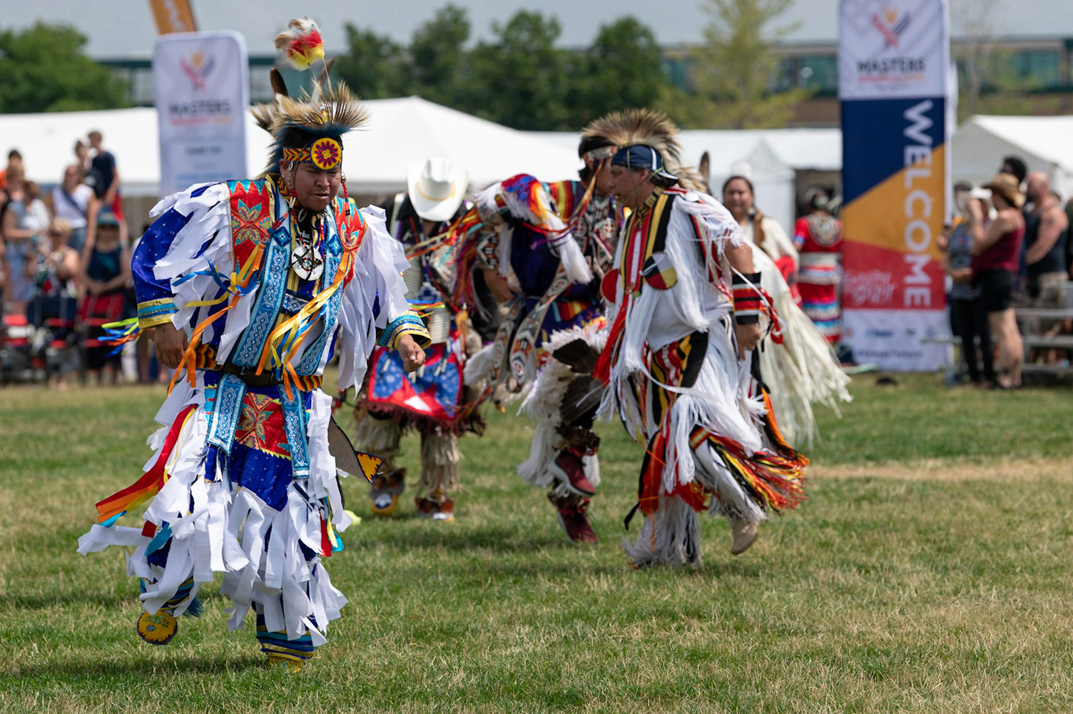 Indigenous dancers in regalia on a field.