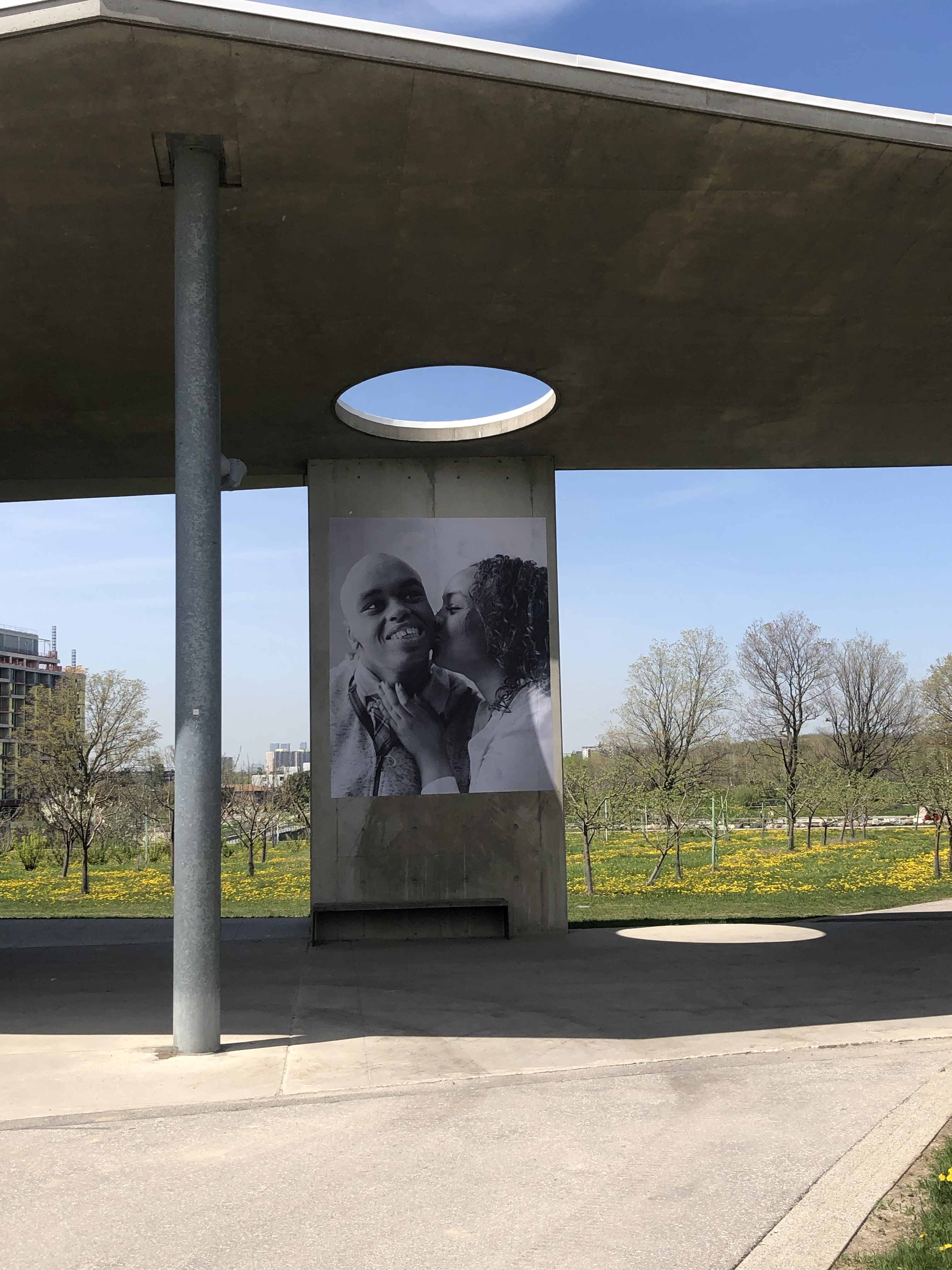 A photo of one person kissing another's cheek on a column of the Orchard Pavilion.