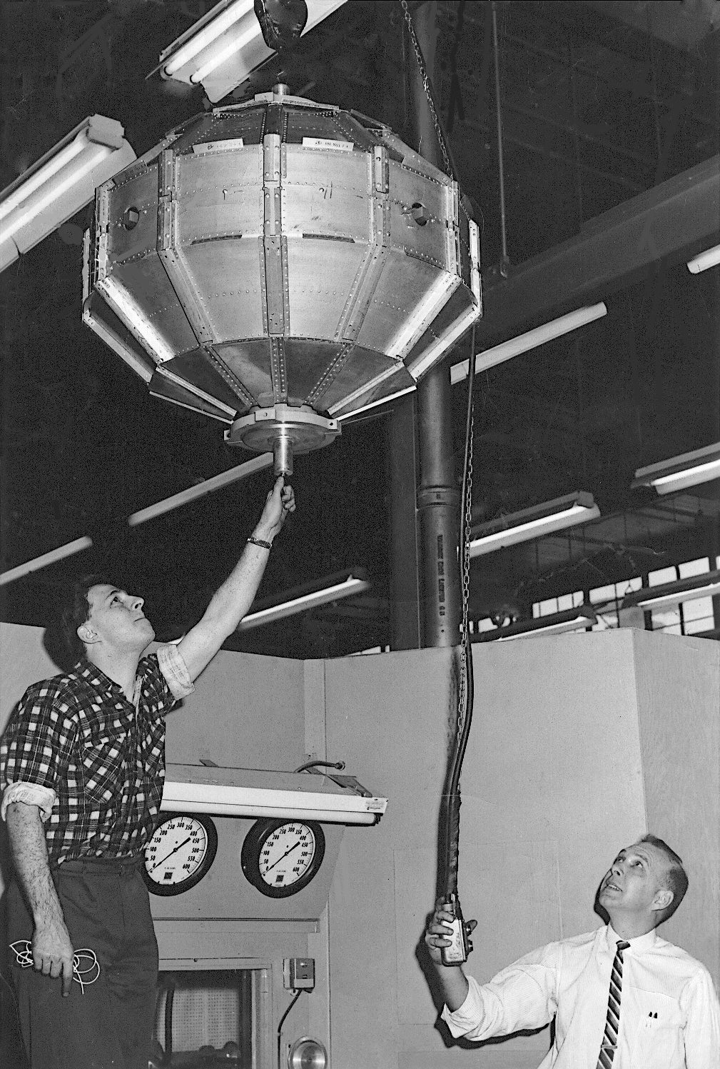 Two people working on the Alouette satellite.