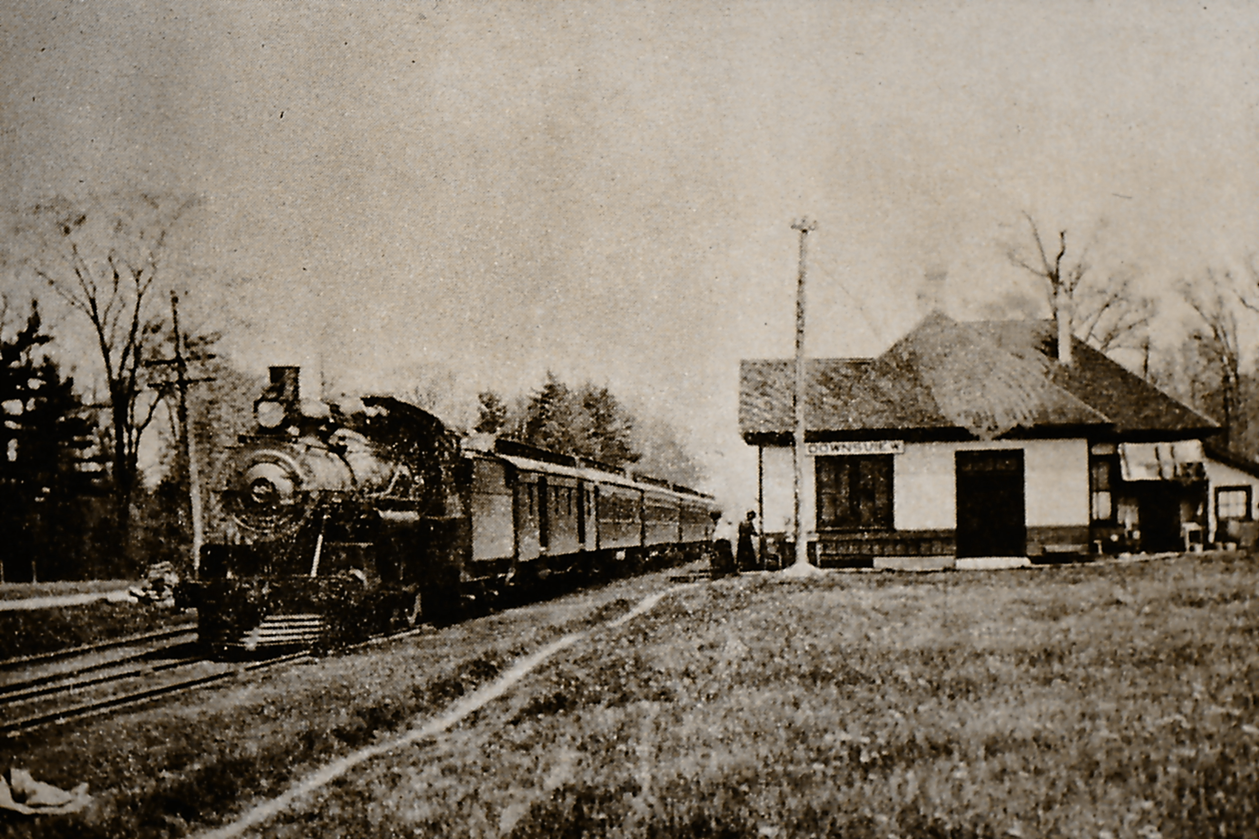 A black and white photo of a train passing through Downsview.