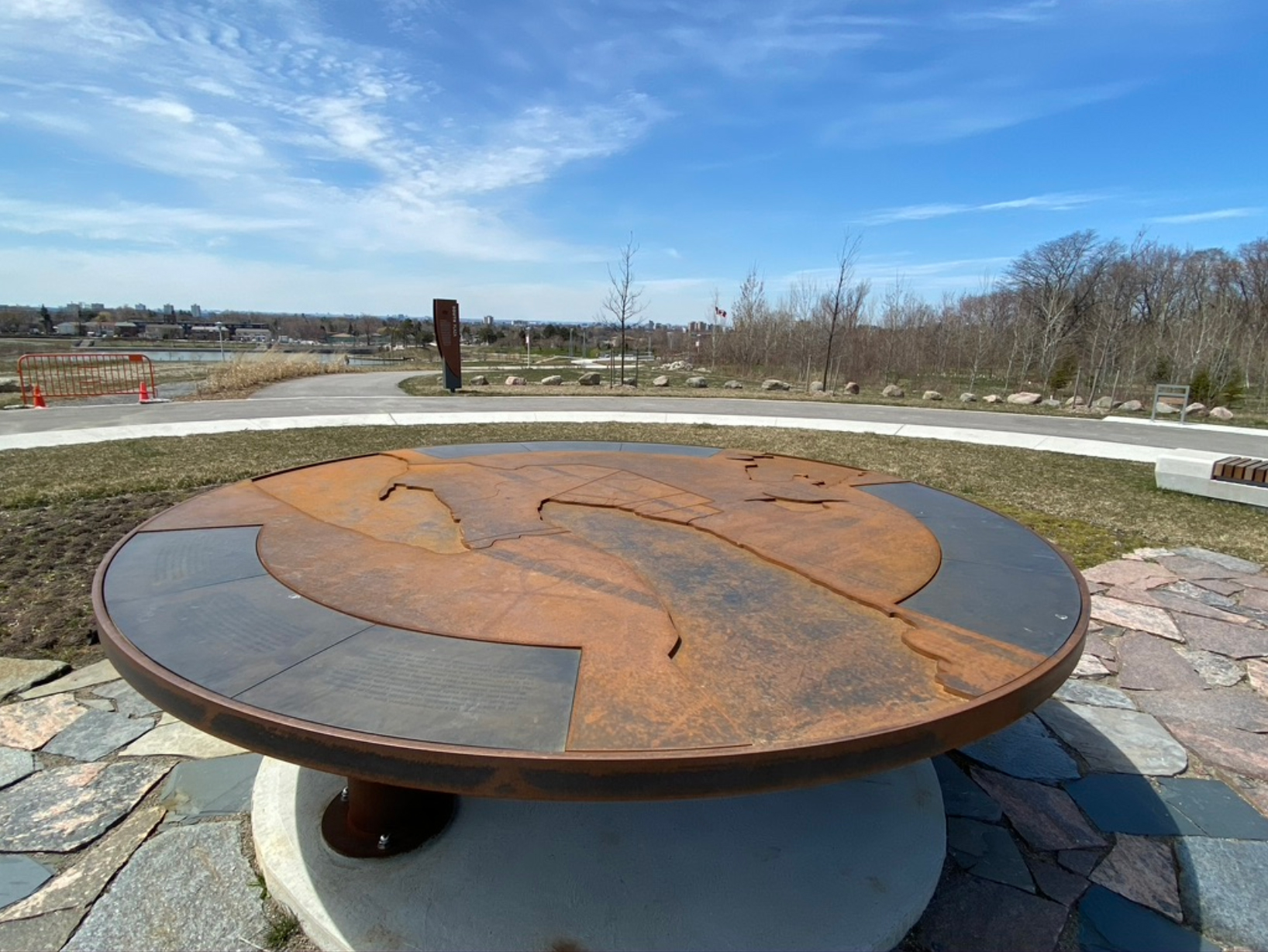 A round corten steel table with a map etched onto its surface.