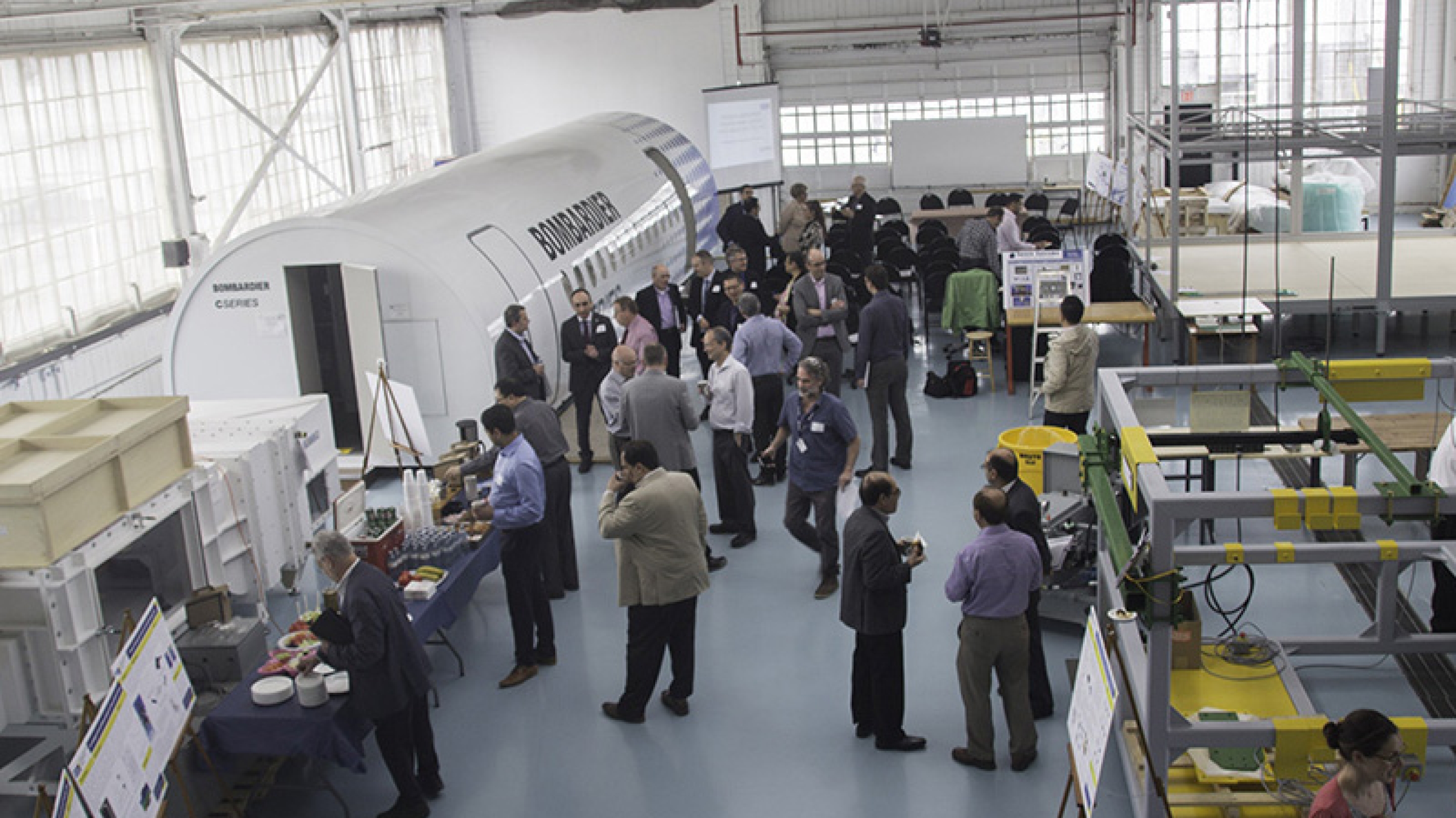 Staff and students gathered indoors around part of a Bombardier aircraft.
