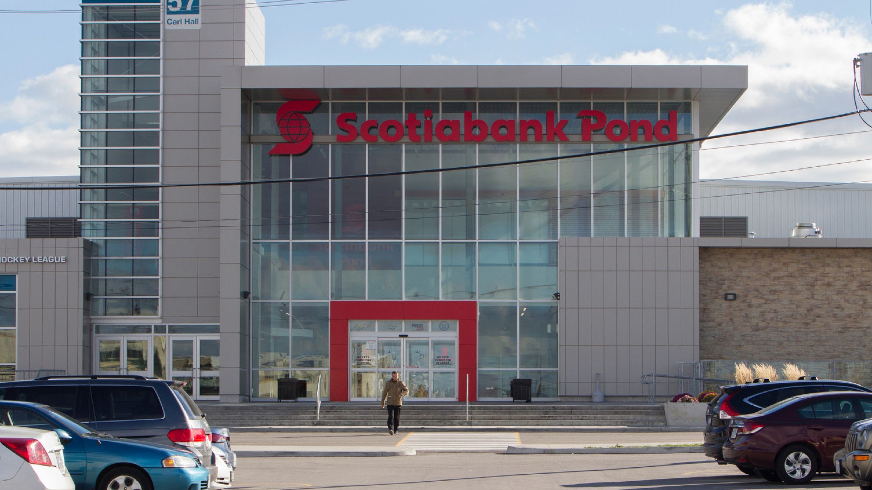 A modern glass building with an entrance outlined in red.