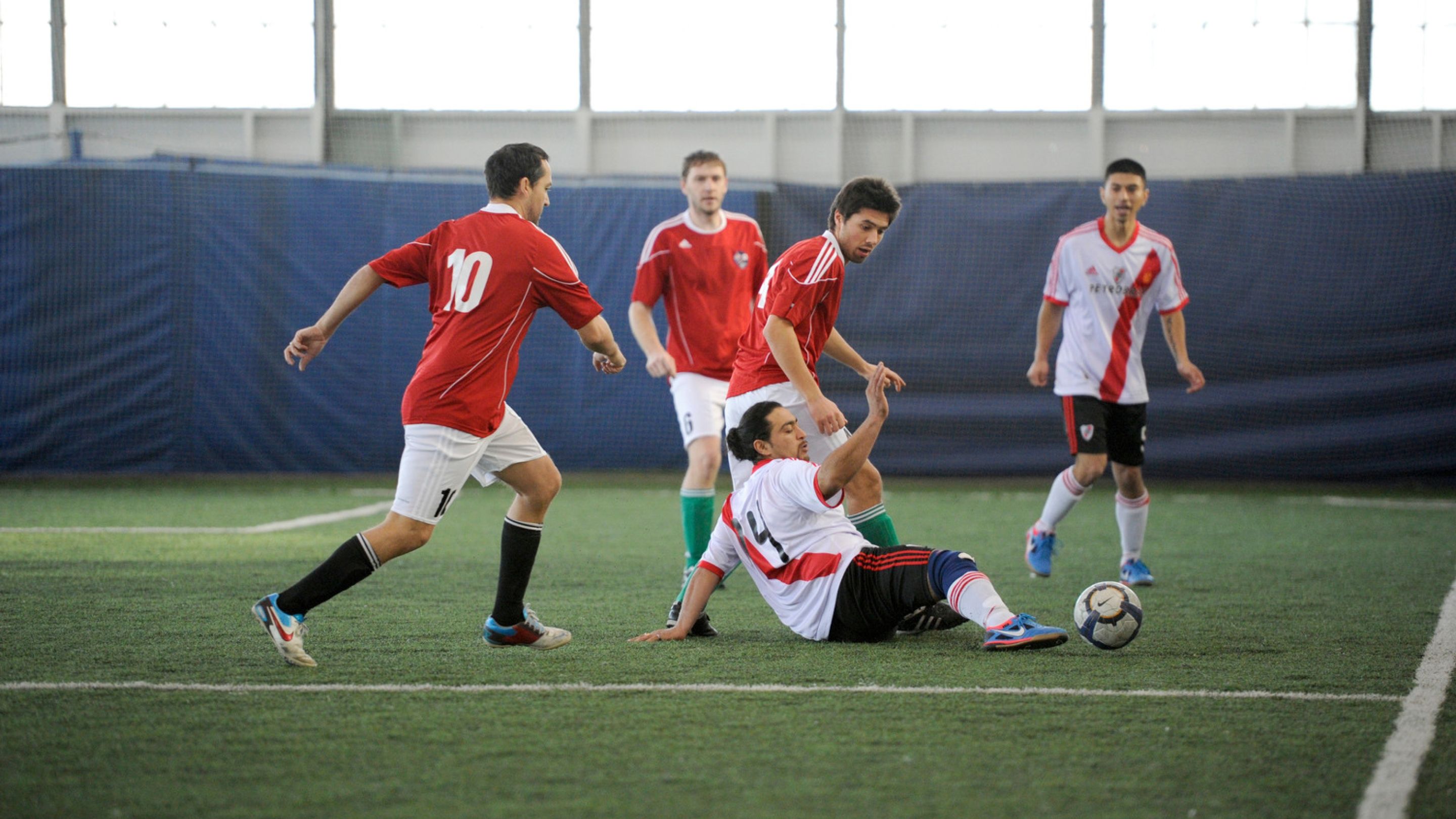 People playing soccer on an artificial indoor turf.