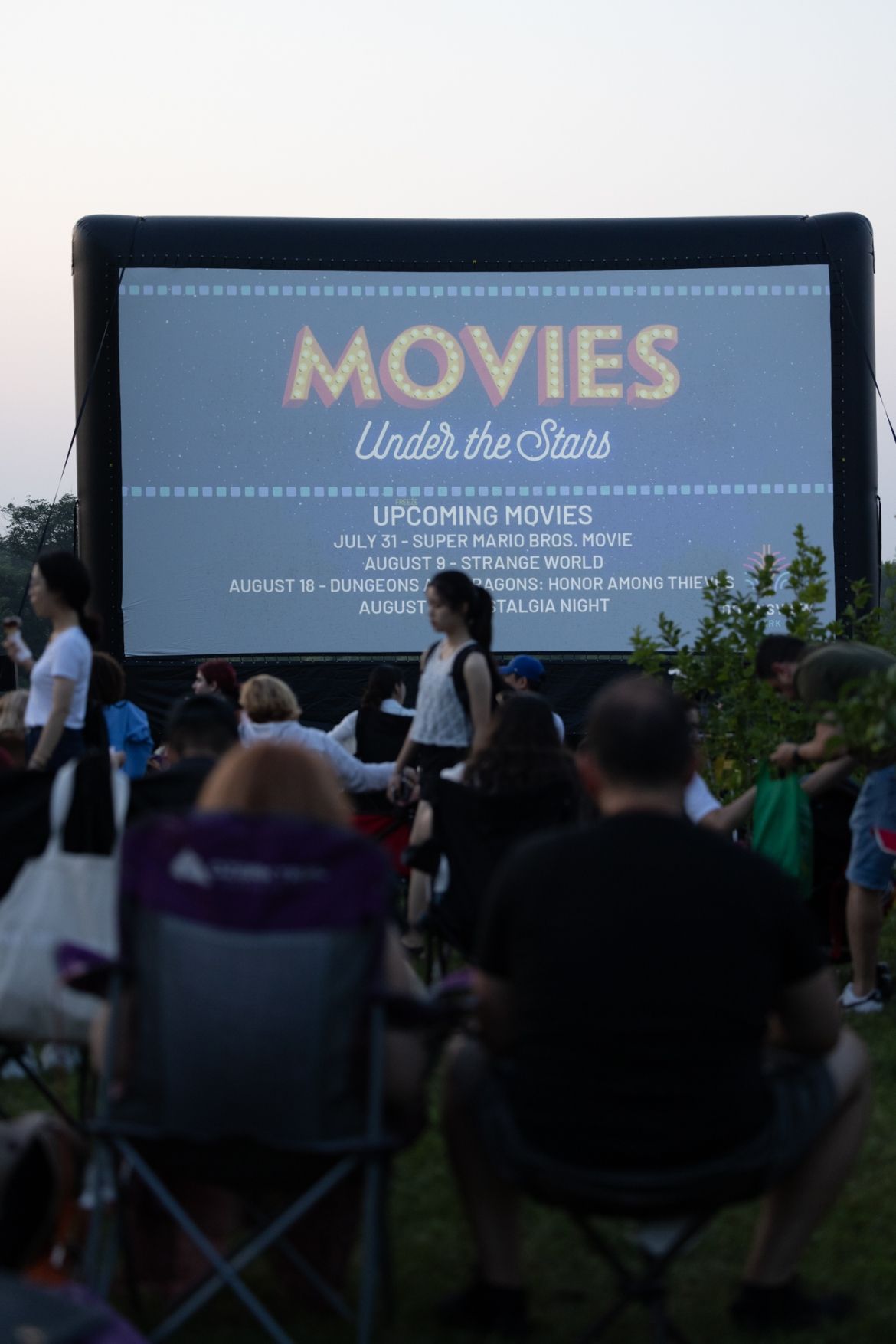people sitting on chairs outdoors watching a movie