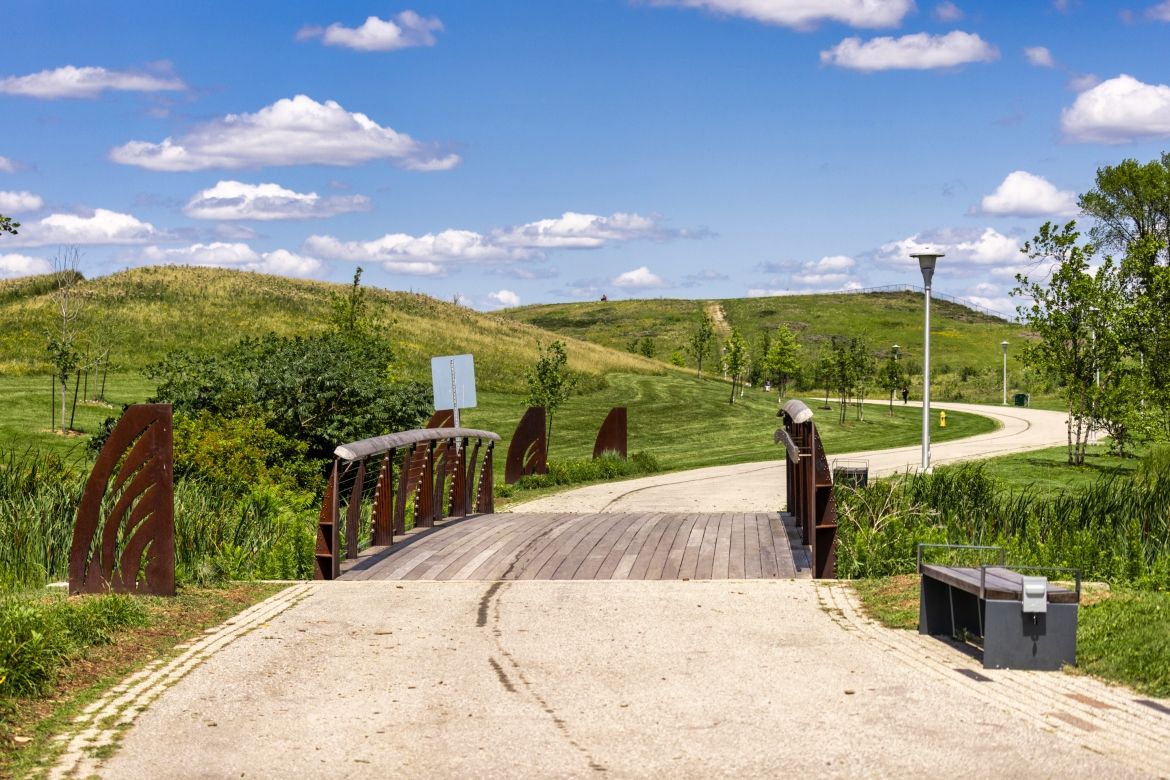 A pedestrian bridge along a paved trail. Below it is a wetland.