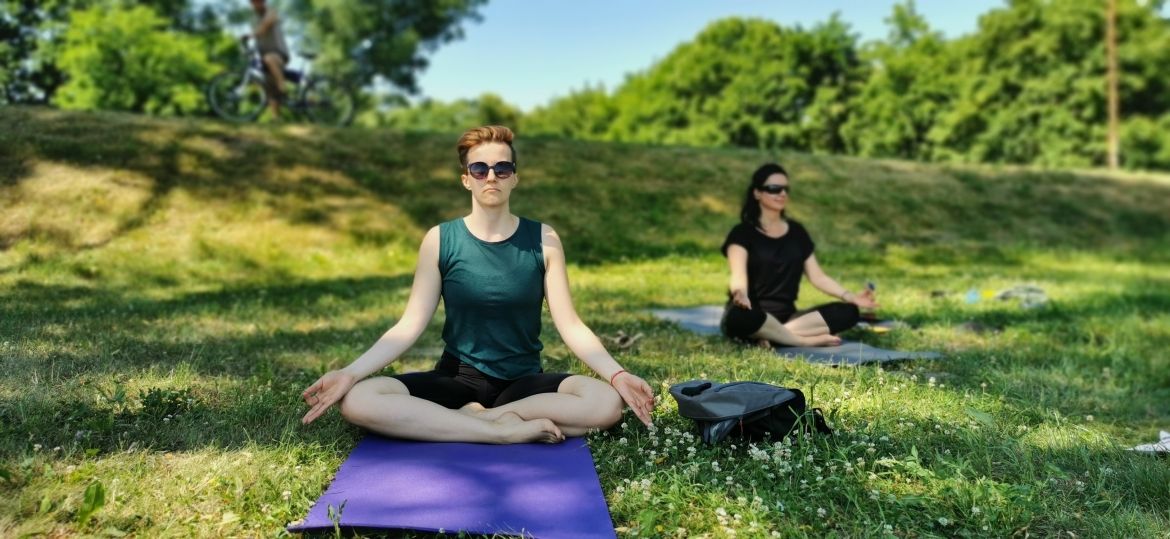 A picture of a fitness group happening in the outdoors with trees and grass in the background.