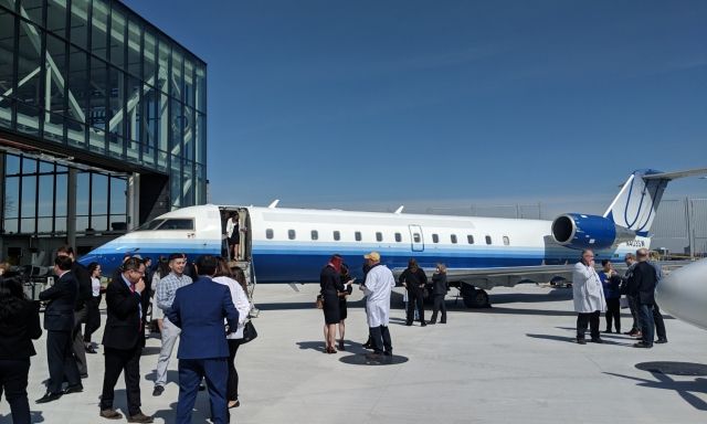 A crowd of people in front of a plane outside of Centennial College.