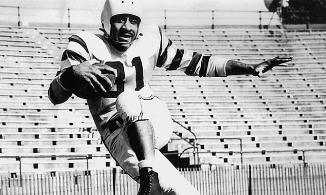 A black and white photo of football player Ulysses &quot;Crazy Legs&quot; Curtis in action during a game.