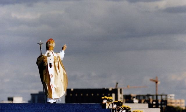 The Pope waving from a platform.