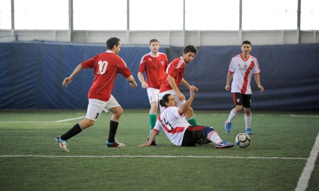 People playing soccer on an artificial indoor turf.