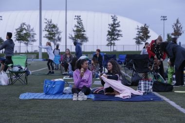 People sitting on a picnic blanket at the Movies Under the Stars event.