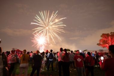 A crowd of people enjoying Canada Day at Downsview Park's Festival Terrace with fireworks