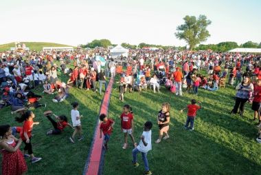 A large crowd of people in red and white celebrating Canada Day on a field.