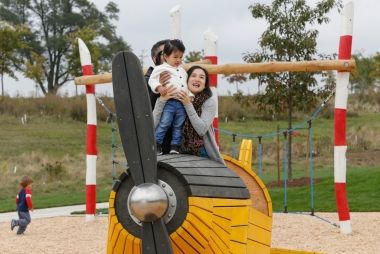 A mom playing with her kid in the yellow model plane at the Play Zone.