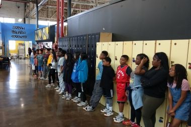 Kids and youth lined up along some lockers.
