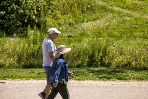 Two people walking side by side on a paved path, grass on either side.