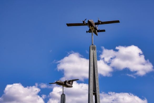 A close-up shot of the model plane installations at the lookout point. A blue sky and white clouds in the background.