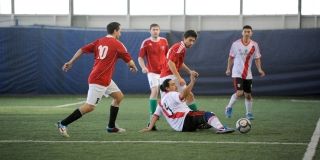People playing soccer on an artificial indoor turf.