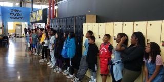 Kids and youth lined up along some lockers.